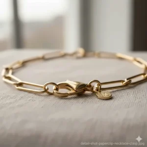 Detailed view of the secure lobster clasp and the precise craftsmanship of the individual gold paperclip chain links.