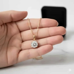 Diamond solitaire pendant necklace in 14k gold shown resting on a hand to illustrate the actual size and scale of the pendant.