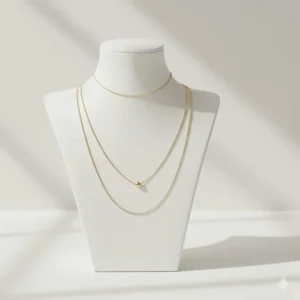 A minimalist gold necklace layering set with two thin cable chains and a small gold bead detail.