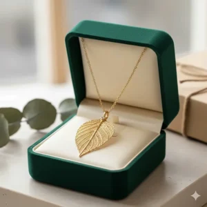 A delicate gold leaf pendant necklace presented in a luxury velvet jewelry box.