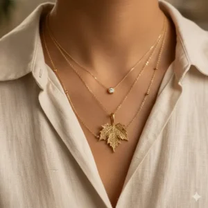 A delicate gold leaf necklace layered with other fine gold jewelry for a modern look.