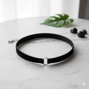 A minimalist black velvet choker necklace laid flat on a white marble surface.