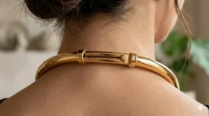 Close-up of the adjustable sliding clasp on a sleek metal collar necklace.